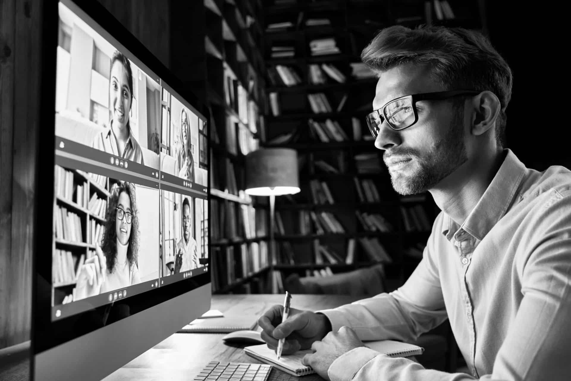 Business man having virtual team meeting on video conference call using computer. Social distance employee working from home office talking to diverse colleagues in remote videoconference online chat.